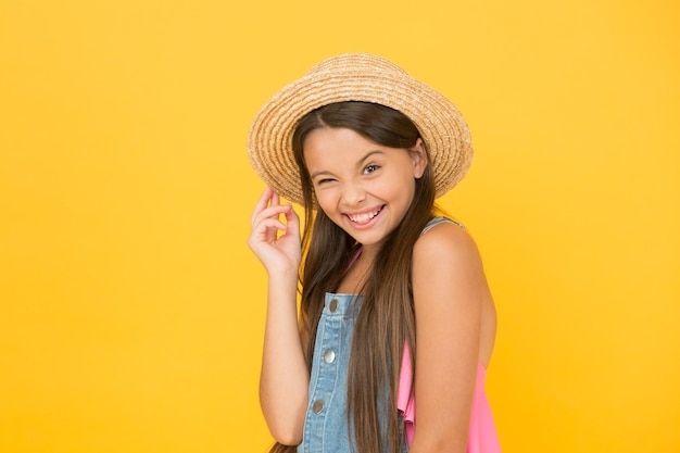 Plein de joie enfance heureuse joyeuse petite fille porter un chapeau de paille mode de plage pour les enfants petit enfant sur fond jaune joie de vacances et activité beauté vacances d'été tant attendues