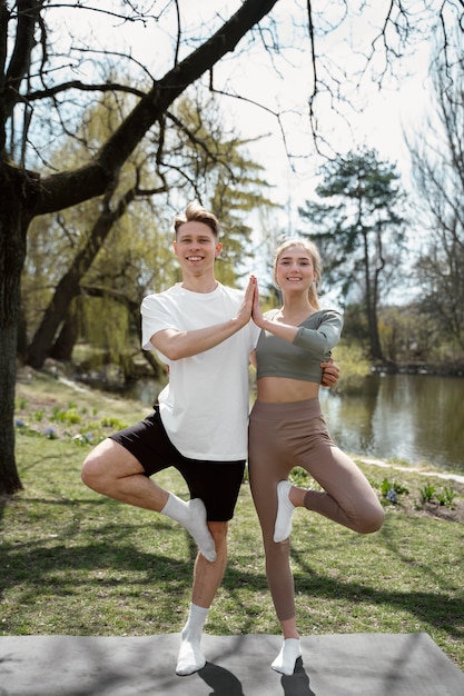 Plein de personnes souriantes faisant de l'exercice ensemble sur un tapis de yoga