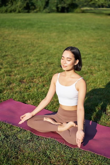 Pleine conscience et méditation jeune femme asiatique souriante tout en faisant du yoga relaxant dans l'asana sur ma en caoutchouc