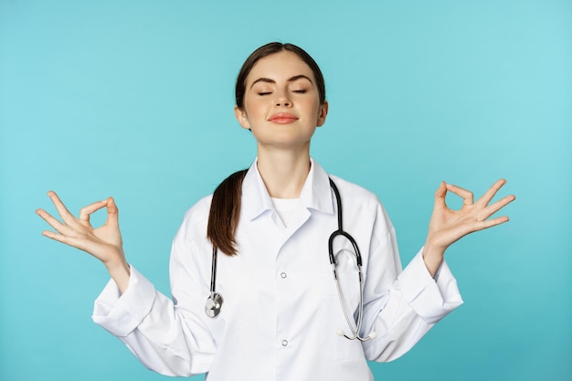 Pleine conscience et méditation patiente jeune femme médecin garder calme tenir la main dans le geste de mudra namaste ...