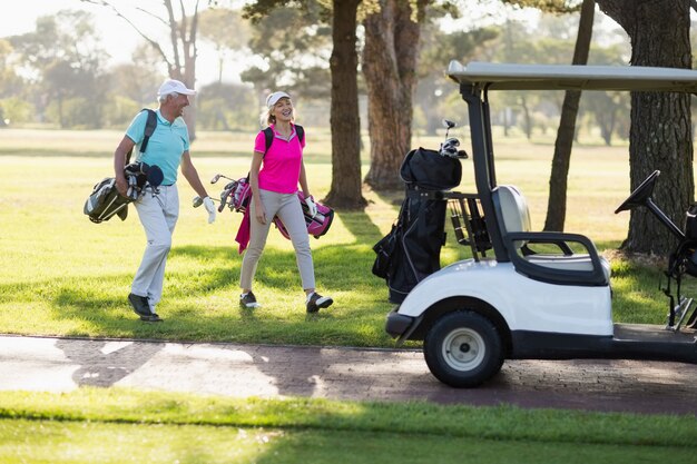 Pleine longueur de couple de golfeurs matures par buggy de golf