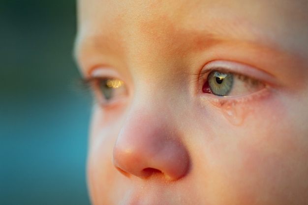 Pleure bébé aux yeux bleu ciel. Petit garçon tendre qui pleure. Goutte pour les yeux, larme de petit enfant chéri. Bébé émotif manque sa maman. Notion d'enfance.