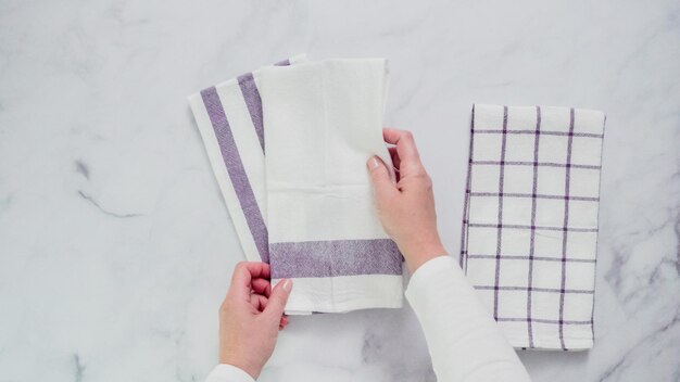 Pliage de serviettes en papier à motifs bleus et blancs sur une surface en marbre.