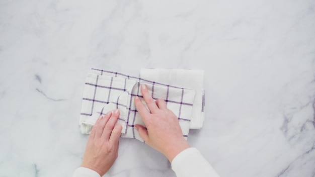 Pliage de serviettes en papier à motifs bleus et blancs sur une surface en marbre.