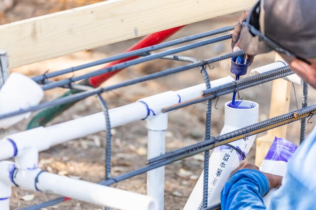 Plombier appliquant du nettoyant et de la colle sur un tuyau en PVC sur un chantier de construction