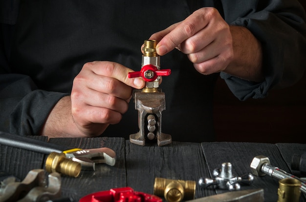 Le plombier connecte les raccords en laiton tout en réparant l'équipement. Gros plan sur la main du maître pendant le travail en atelier