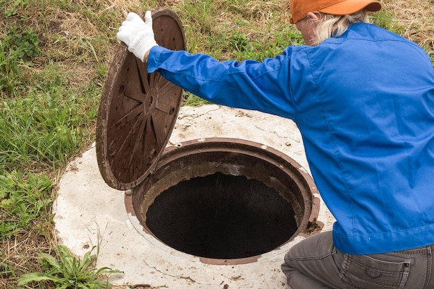 Un plombier ouvre une trappe d'égout Entretien des fosses septiques et des puits d'eau