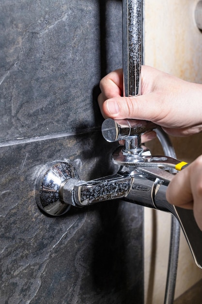 Plombier réparant le vieux robinet de douche sur le mur carrelé