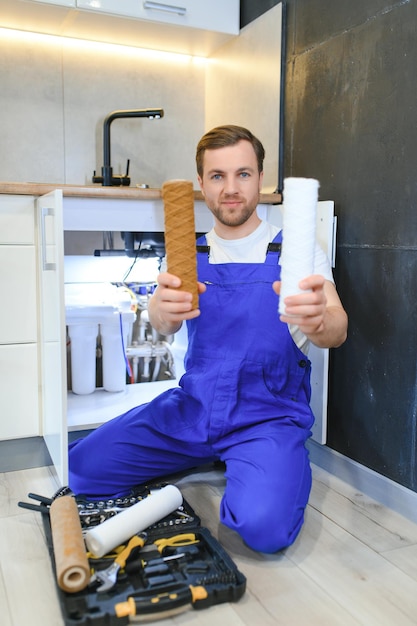 Photo plombier travaillant changer le filtre à cartouche pour l'eau dans la cuisine système de filtration concept