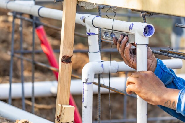 Plombier utilisant le niveau lors de l'installation d'un tuyau en PVC sur un chantier de construction