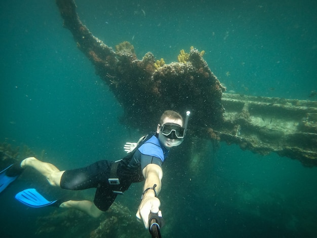 Plongeur libre prenant selfie avec bateau coulé sur fond.