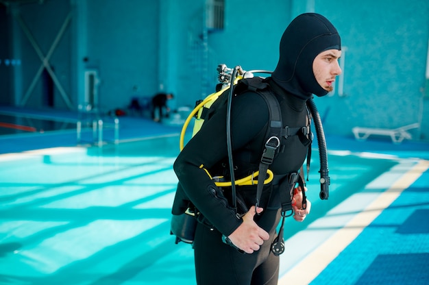 Photo plongeur masculin en combinaison de plongée se prépare pour la plongée, école de plongée. enseigner aux gens à nager sous l'eau, intérieur de la piscine intérieure sur fond