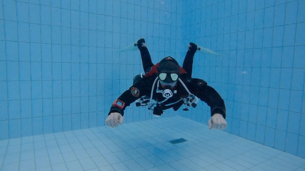 Photo plongeur sous-marin dans la piscine avec des réservoirs de montage latéral