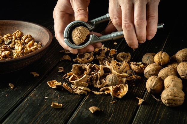 Éplucher les noix avec un casse-noix par les mains d'un cuisinier