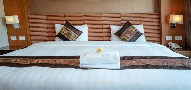 Plumeria et serviettes sur le lit dans la chambre d'hôtel de luxe prêt pour les voyages touristiques.