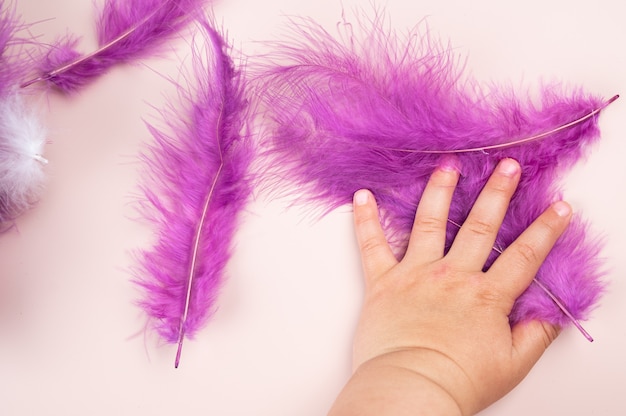 Plumes multicolores dans la main d'un enfant.