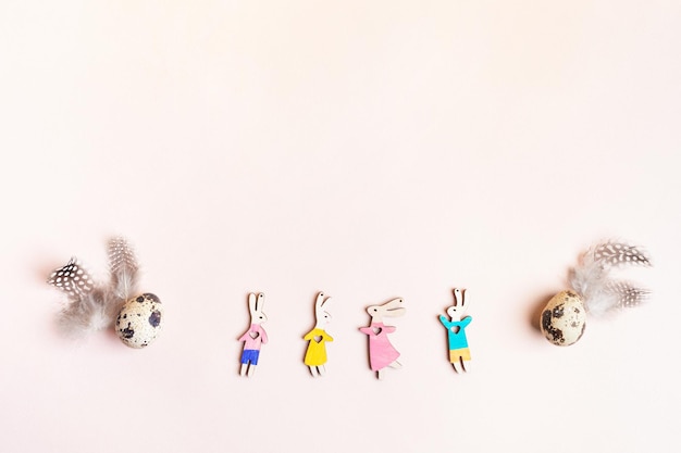 Plumes d'oeufs de lapins en bois drôles colorés comme arc sur l'image de Pâques rose espace de copie vue de dessus