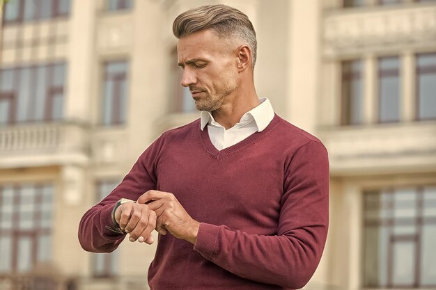 Plus qu'un dispositif d'indication de l'heure L'homme vérifie la montre en plein air urbain Un bel homme porte une montre-bracelet L'utilisation d'une montre intelligente dans la vie personnelle et professionnelle Mode de vie moderne Sa montre reflète son statut