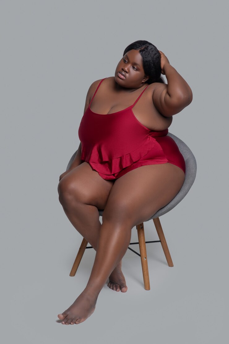Plus la taille jeune femme en sous-vêtements rouges assis sur une chaise et à la détente
