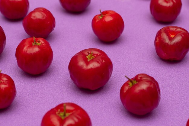 Plusieurs acérolas sur fond lilas