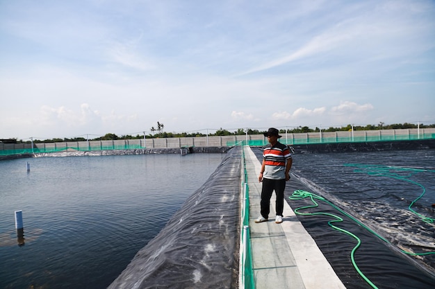Photo plusieurs agriculteurs surveillent la culture des crevettes vannamei depuis le bord de l'étang en pehd