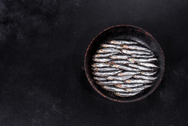 Photo plusieurs anchois salés sur une table de béton sombre