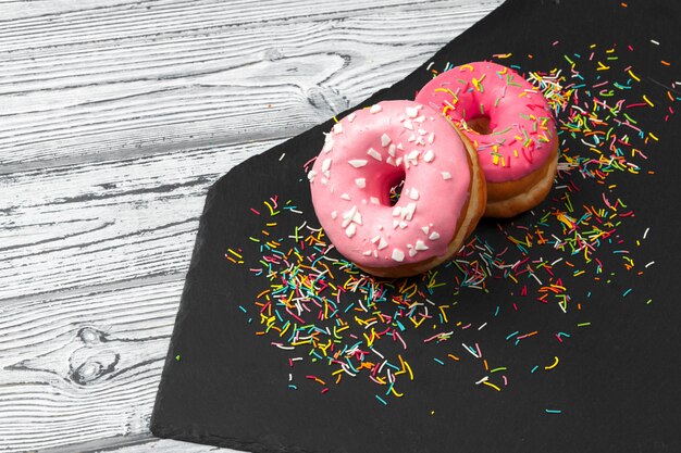 Plusieurs beignets frais dans une assiette en céramique noire sur une table en bois