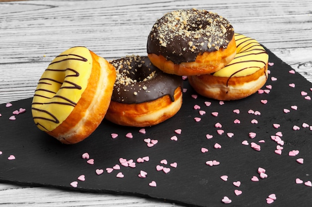 Plusieurs beignets frais dans une assiette en céramique noire sur une table en bois