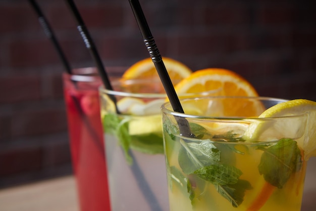 Plusieurs boissons différentes sur la limonade de table dans une tranche de verre de citron et de pailles fond sombre à l'intérieur