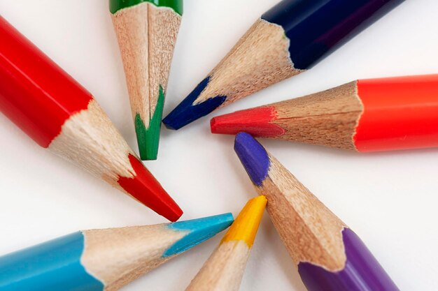 Plusieurs crayons multicolores sont disposés en cercle sur un fond blanc gros plan macro