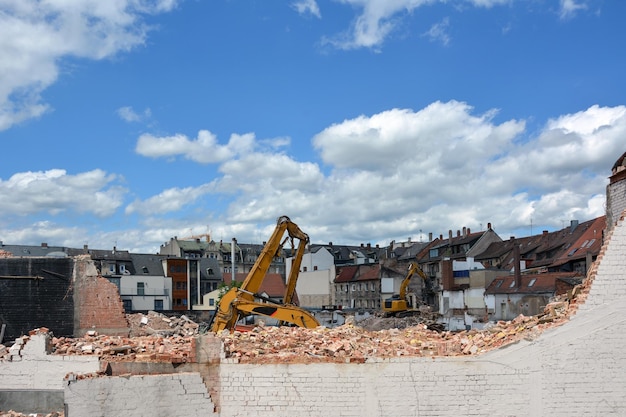 Plusieurs excavatrices de construction sont engagées dans le démantèlement d'une vieille maison Démantèlement de la ville