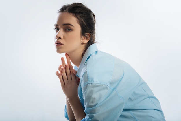 Plusieurs façons. Pensive jolie jolie femme se frottant les mains tout en regardant la caméra et en tournant le visage vers la caméra