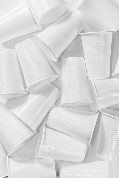 Plusieurs gobelets en plastique jetables sur fond blanc. Nature morte minimaliste et écologique. Concept de problème de technologie verte et d'écologie.