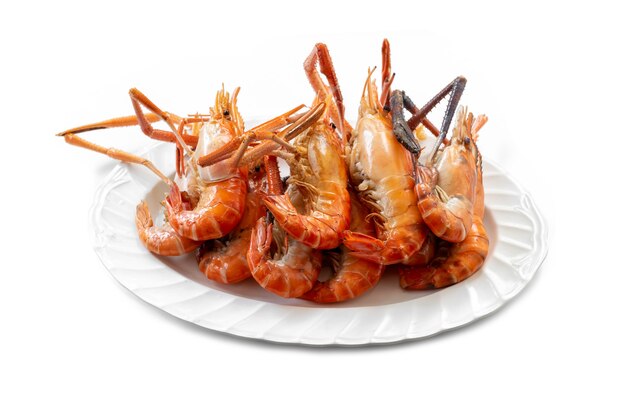 Plusieurs grosses crevettes de rivière grillées et placées sur une assiette sont prêtes à manger sur fond blanc.