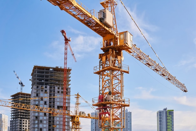 Plusieurs grues à tour de construction de différentes hauteurs sur un chantier pendant la construction