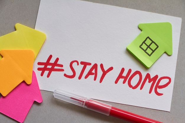 Plusieurs maisons en papier multicolores avec hashtag Stay Home et marqueur rouge. Restez à la maison.