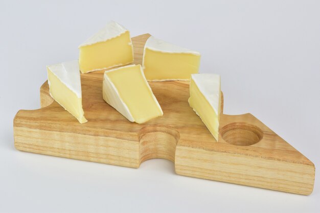 Photo plusieurs morceaux de fromage camembert se trouvent sur un support en bois spécial pour le fromage sur une surface de coupe blanche