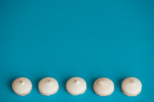 Plusieurs petits biscuits blancs disposés en rangée sur du bleu