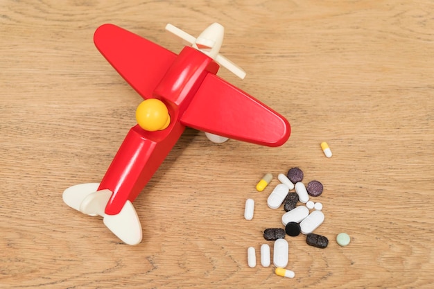 plusieurs pilules et un avion jouet sur une vieille table en bois