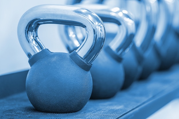 Plusieurs poids noirs poids différents. Poids en métal noir kettlebell une rangée. Kettlebells sportifs dans un club de sport. Équipement de musculation. Tonifiant