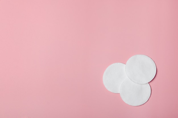 Plusieurs tampons de coton pour enlever le maquillage sur un rose