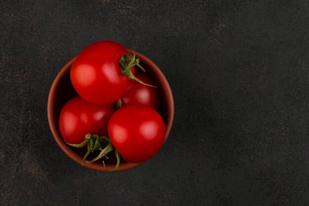 Plusieurs tomates cerises dans un bol d'argile sur dark