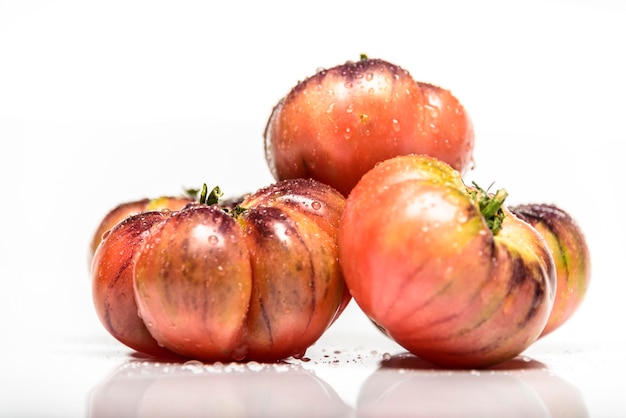Plusieurs tomates de la variété tigrée sur fond blanc