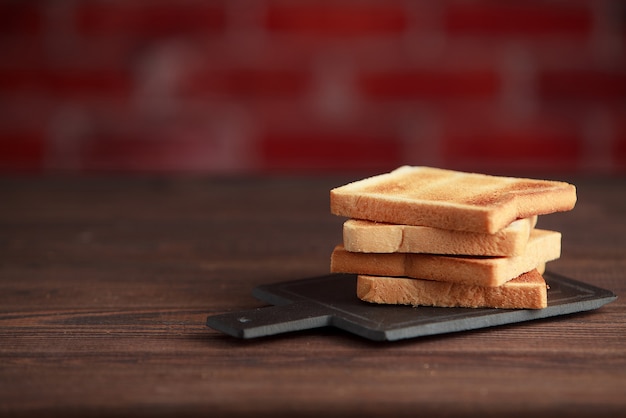 Plusieurs tranches de pain grillé toasts sur un fond sombre en bois.