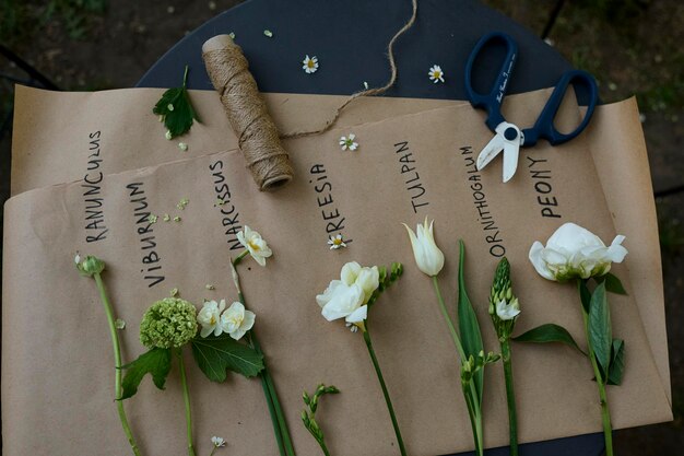 Plusieurs types de fleurs blanches disposées sur du papier parchemin sur une table dans le jardin