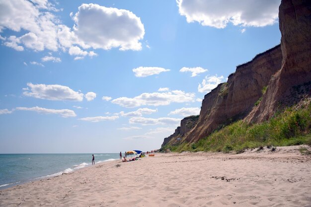 Plusieurs vacanciers se détendent et bronzent sur la plage de sable de la mer