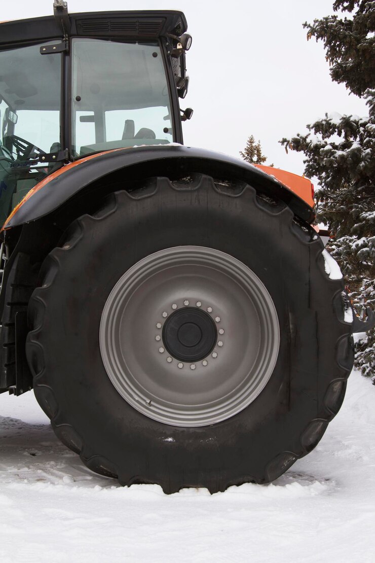 Photo pneu de roue d'un tracteur agricole au jour de neige d'hiver, gros plan