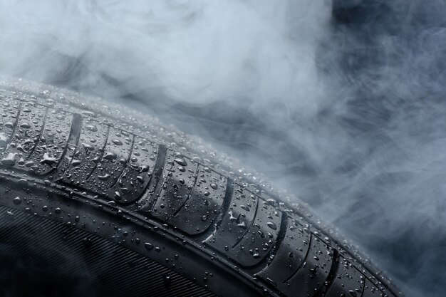 Pneu de voiture recouvert de gouttes d'eau dans le brouillard