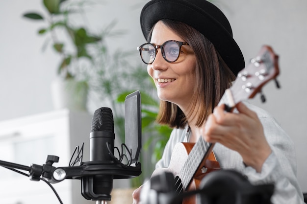 Podcast musique création de contenu audio belle femme européenne podcasteur dans un chapeau avec une guitare ou