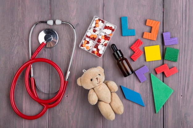 Podiatre en milieu de travail stéthoscope ours jouet et médicaments sur le bureau en bois concept de soins de santé pour enfants